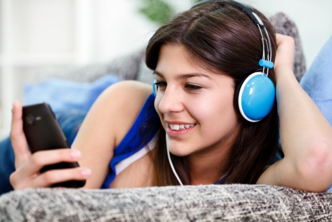 Teenager holds smartphone and listens to music