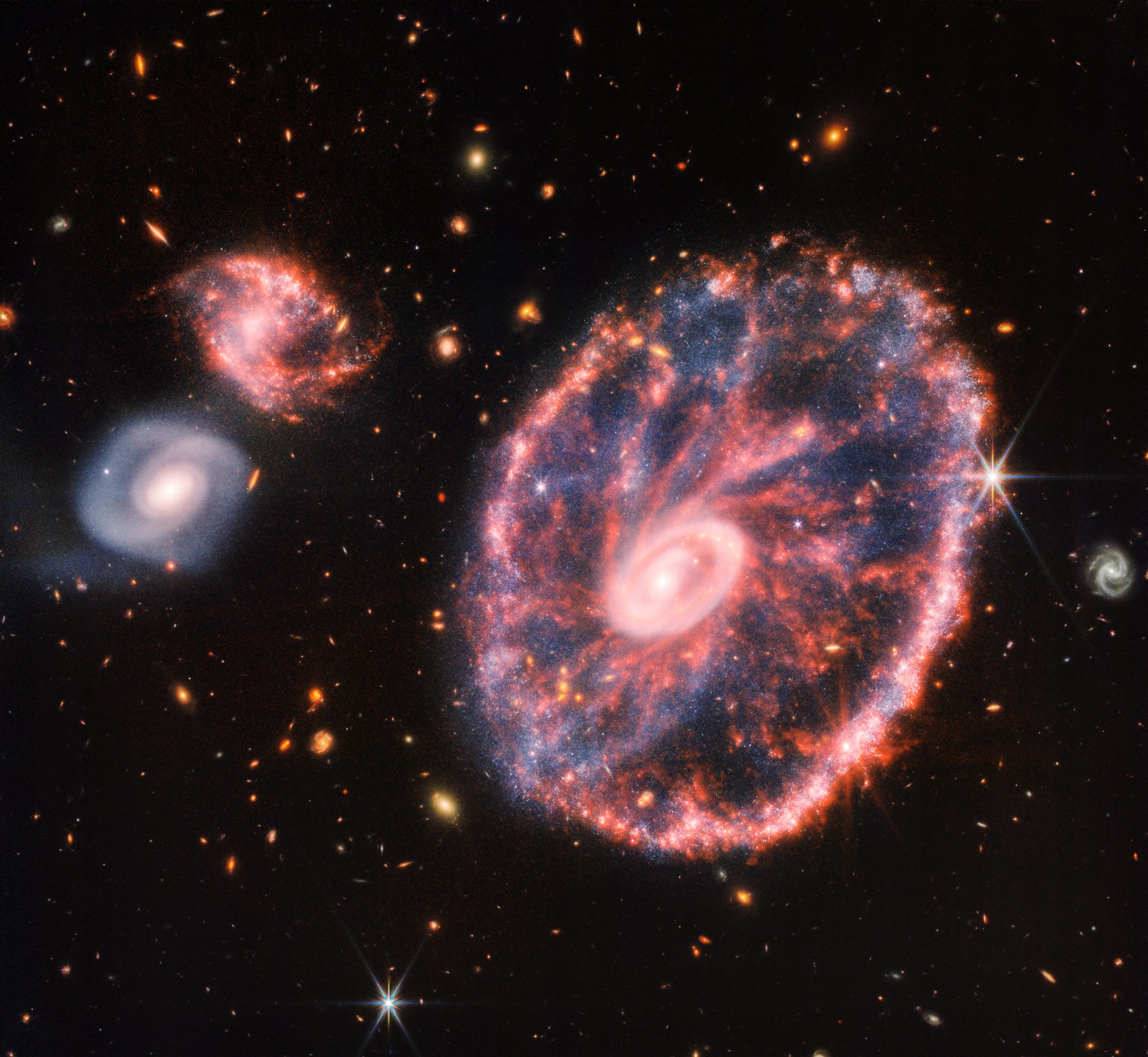Складене зображення галактики Колесо Воза, отримане приладами JWST NIRCam та MIRI. Величезна космічна структура зараз перебуває в перехідному стані після зіткнення з іншою галактикою приблизно 400 мільйонів років тому. Зображення:  NASA, ESA, CSA, STScI, CC BY 2.0