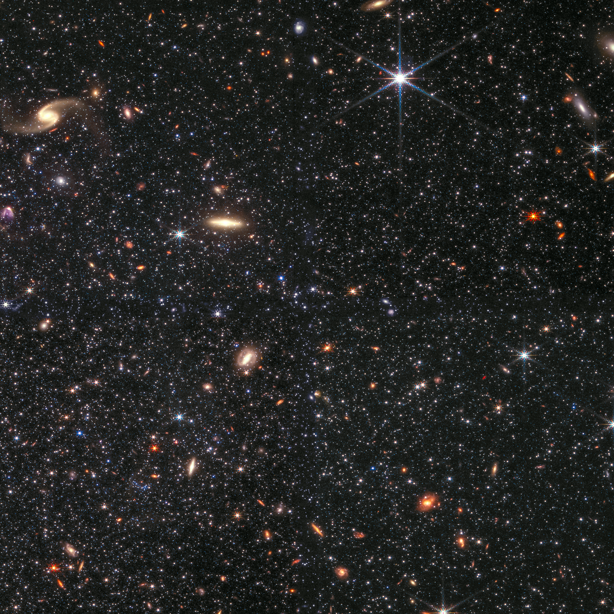 Зірки у карликовій галактиці Вольф-Лундмарк-Мелотте. Також на фоні можна побачити помаранчеві галактики, що сяють позаду зірок. Зображення: NASA, ESA, CSA, STScI та Крістен МакКвін (Університет Рутгерса, CC BY 2.0)
