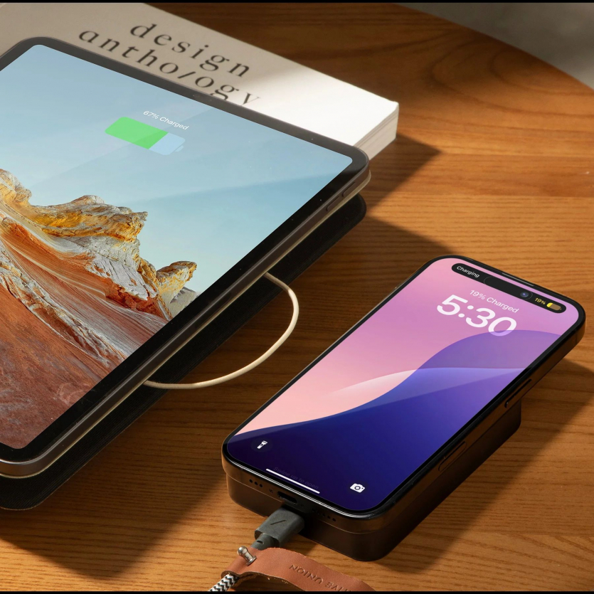 Коричневий магнітний павербанк Native Union (Re)Classic 10000 mAh, прикріплений до iPhone на столі.