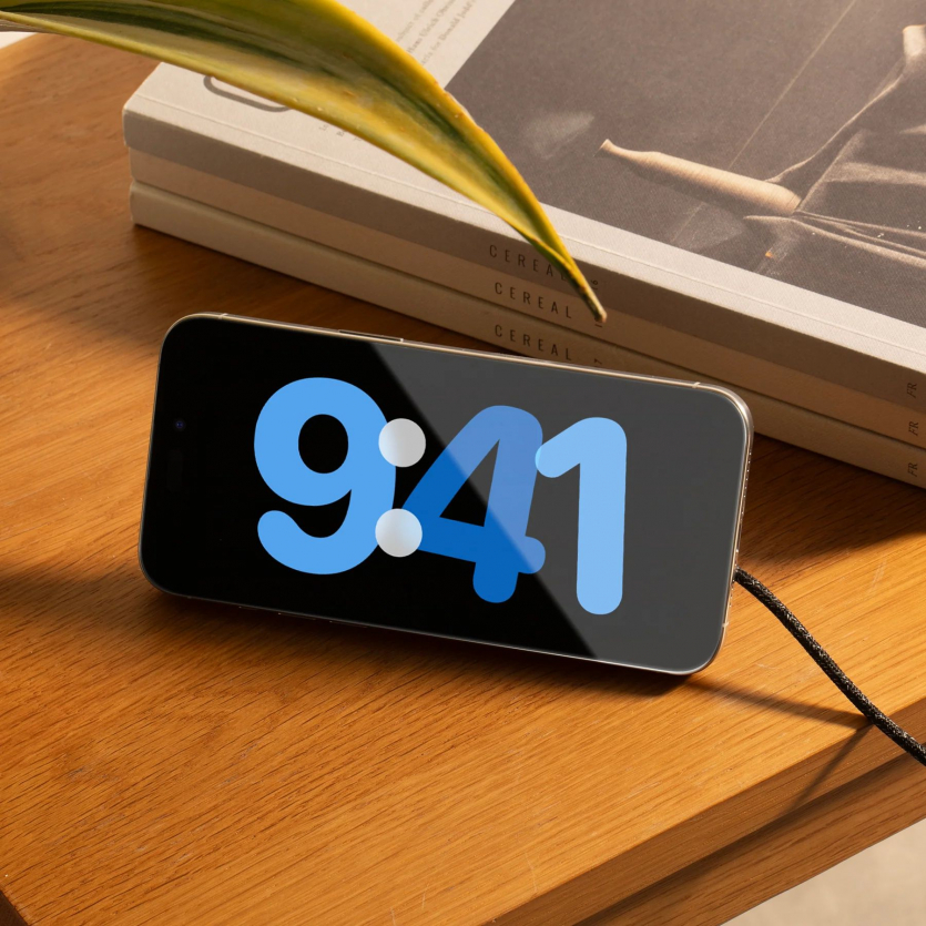 Смартфон iPhone у режимі StandBy на дерев'яному столі з підключеною магнітною зарядкою Native Union SnapStand.