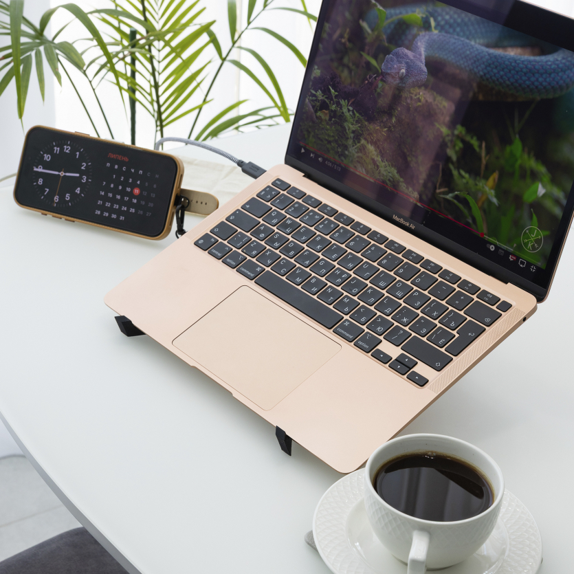 Робочий стіл із MacBook Air, чашкою кави та iPhone у режимі StandBy на зарядці Native Union Voyage 2-in-1 Qi2.