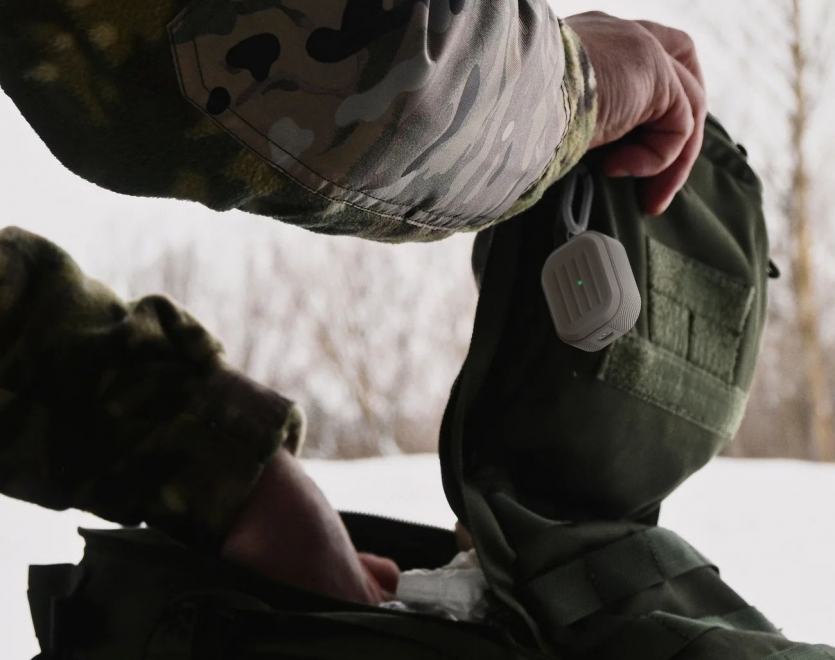 Захисний тактичний чохол Elago Armor Hang Stone для AirPods Pro 3rd Gen на фоні зимового лісу та камуфляжного спорядження.