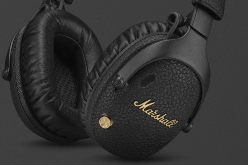 Макрофото чашки навушників Marshall Monitor III: текстура корпусу, золотистий джойстик управління та фірмовий логотип.